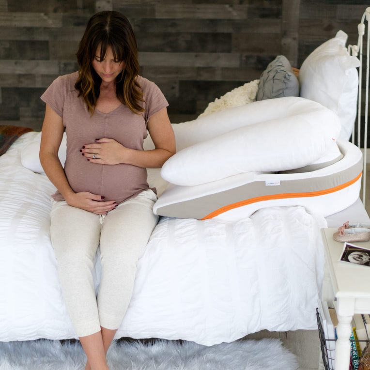 Pregnant woman sitting on bed with MedCline Acid Reflux Relief Pillow, demonstrating the product’s use for acid reflux relief during pregnancy. MedCline’s pillow offers therapeutic support to improve sleep quality.