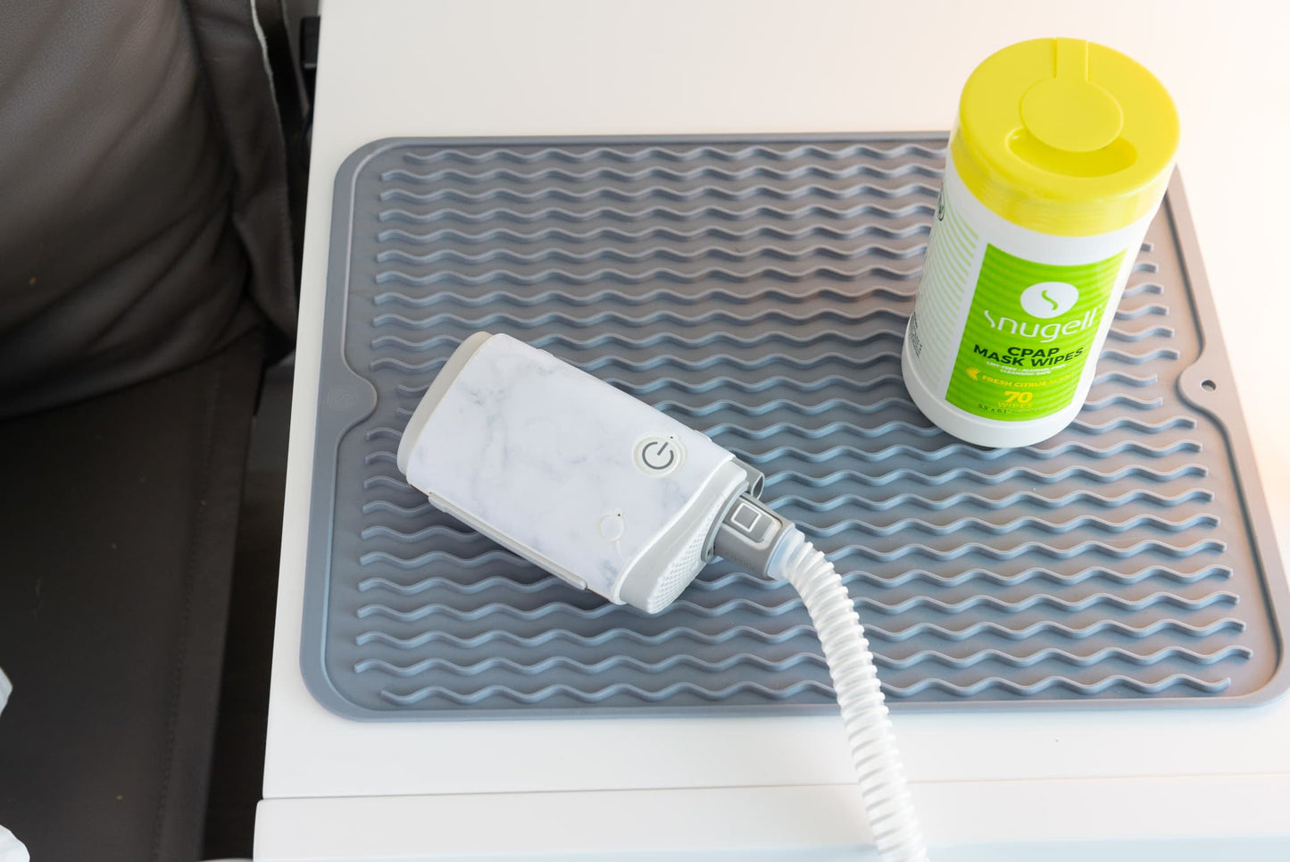 Snugell skin for AirMini Travel CPAP Machine in marble pattern, placed on a gray mat alongside a container of CPAP mask wipes, showcasing stylish and protective covering options for travel CPAP users