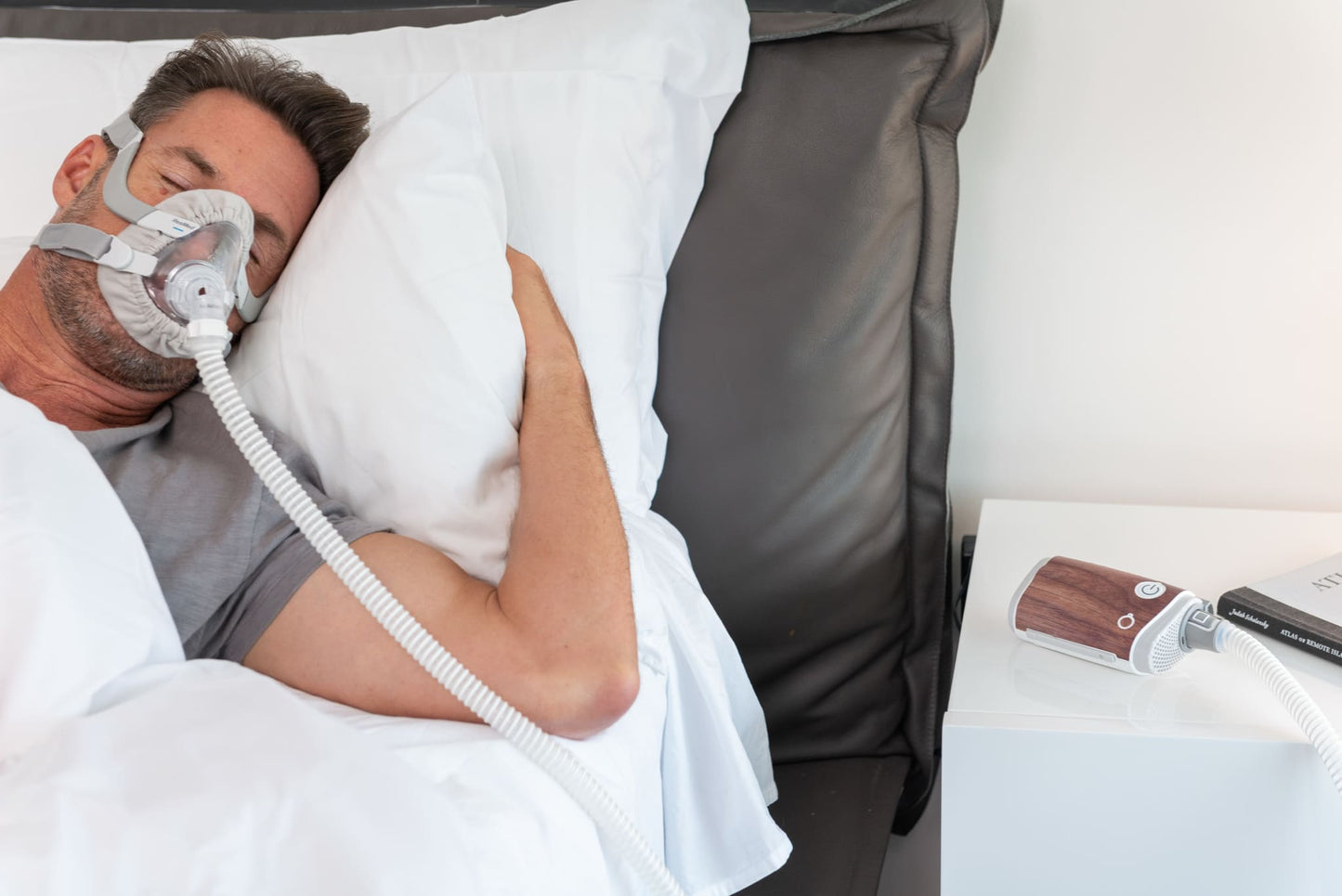 AirMini Travel CPAP Machine with dark wood Snugell skin on a bedside table, offering a warm and cozy aesthetic for nighttime therapy.