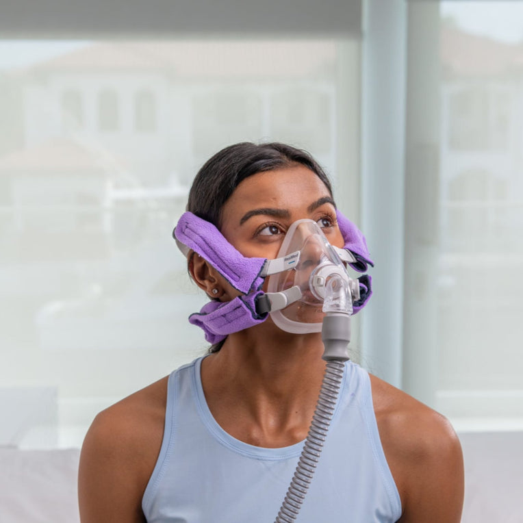 Front view of a woman wearing a CPAP mask with Snugell CPAP strap covers in purple, designed for enhanced comfort during sleep.